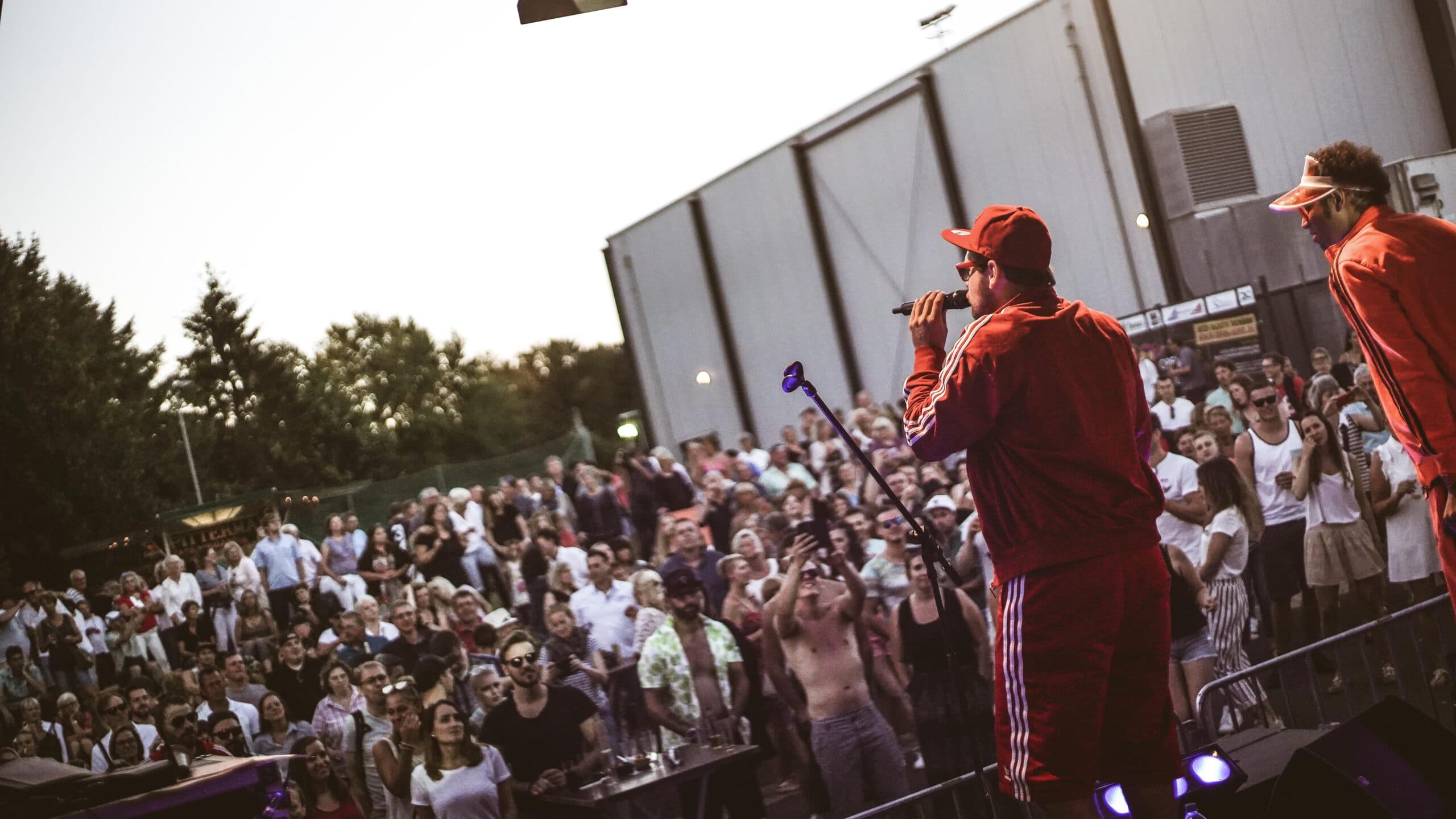 Rapper auf Bühne mit jubelndem Publikum bei Dämmerung